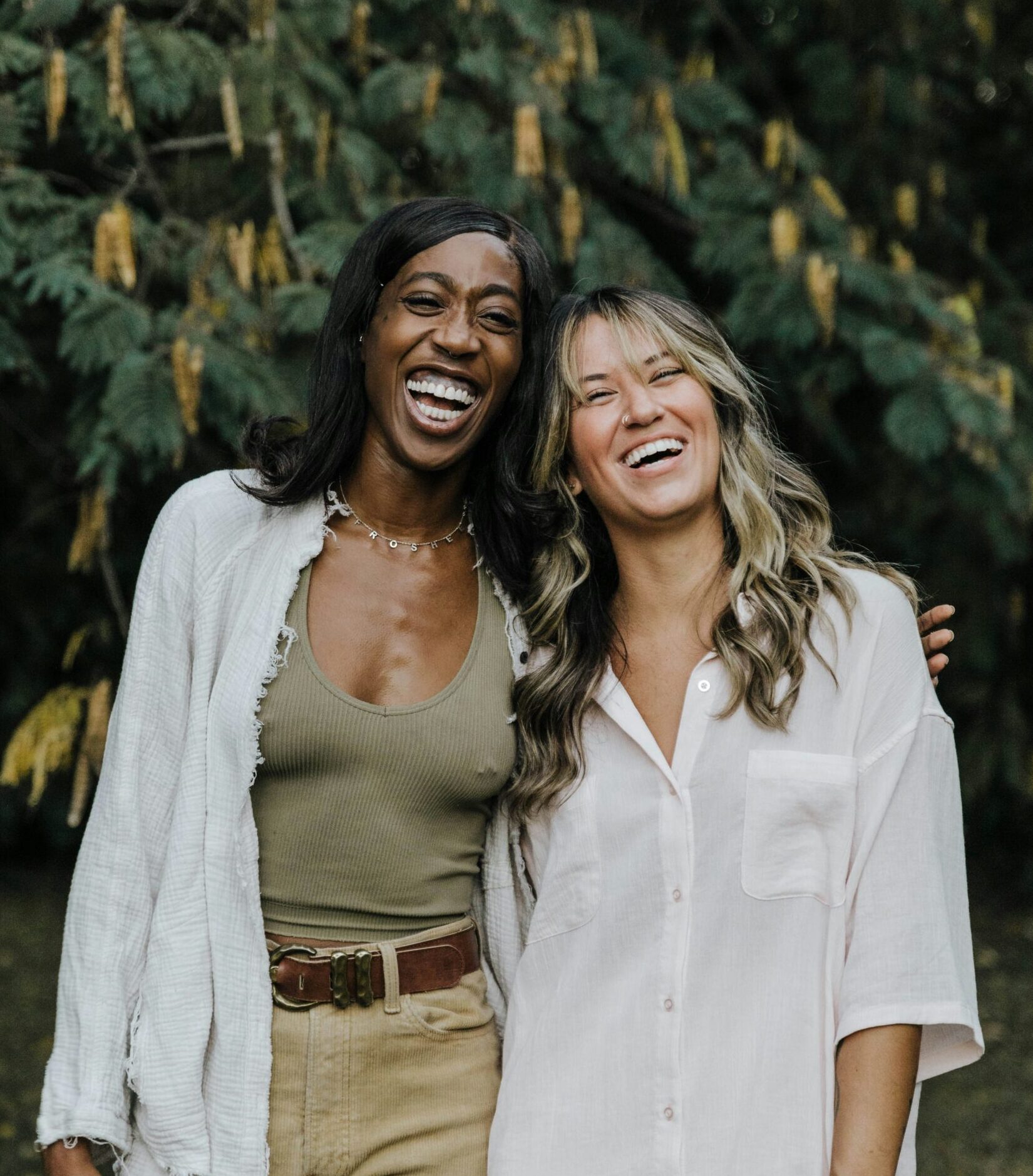 Two women hugging and laughing outside, supporting each other through perimenopause journey.