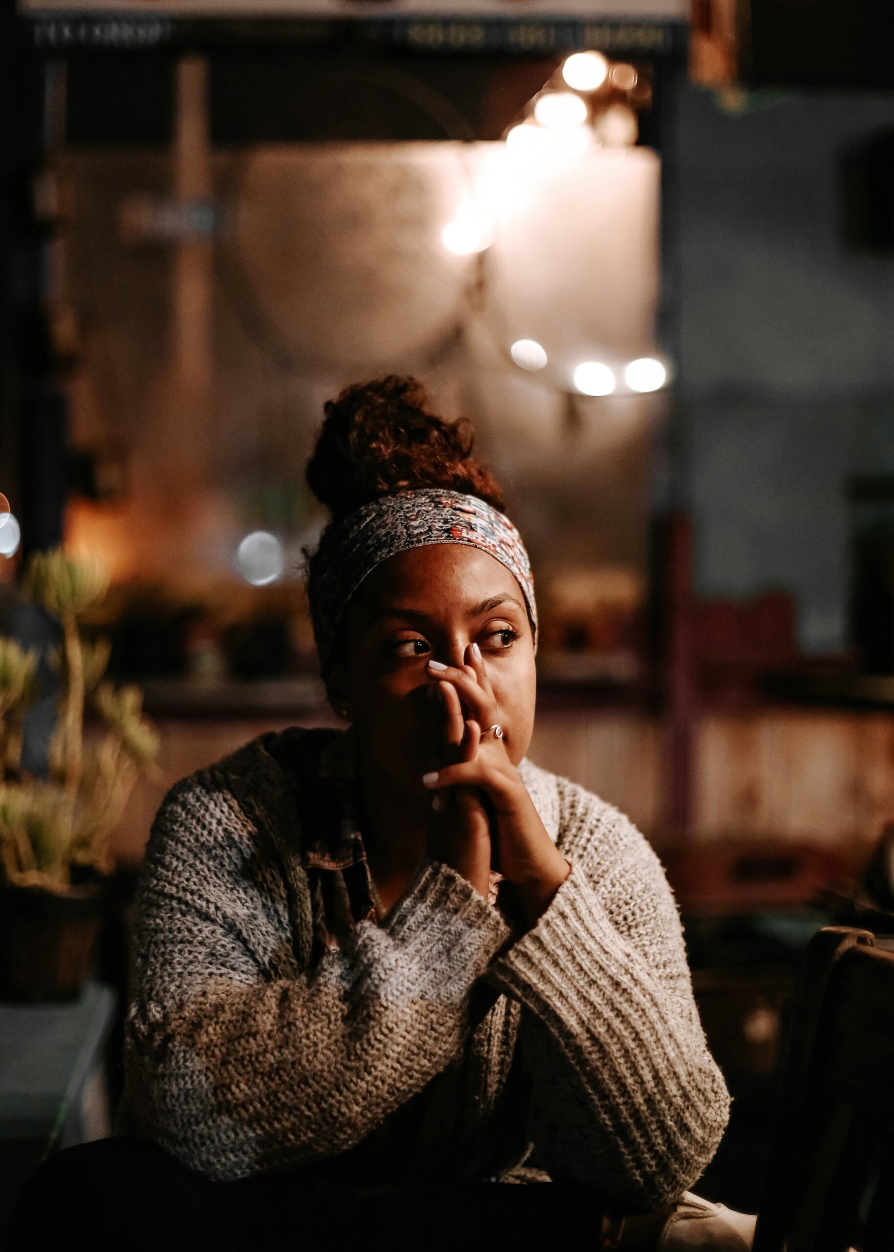 Woman sitting in deep thought at night, reflecting on her purpose and feeling lost in her 40s.