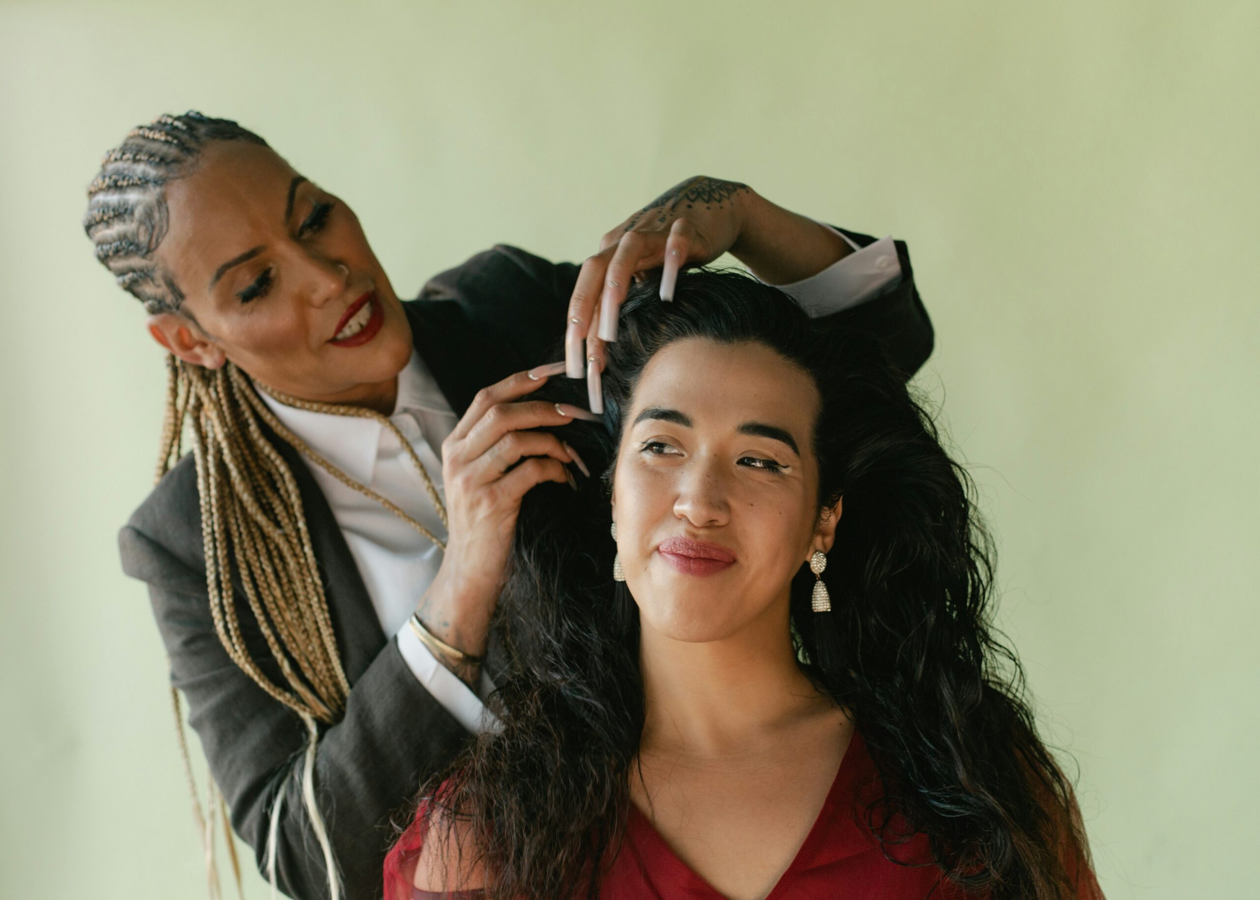 Gender affirming care menopause support shown through two people of diverse gender expressions sharing a moment of care and connection against a soft green background