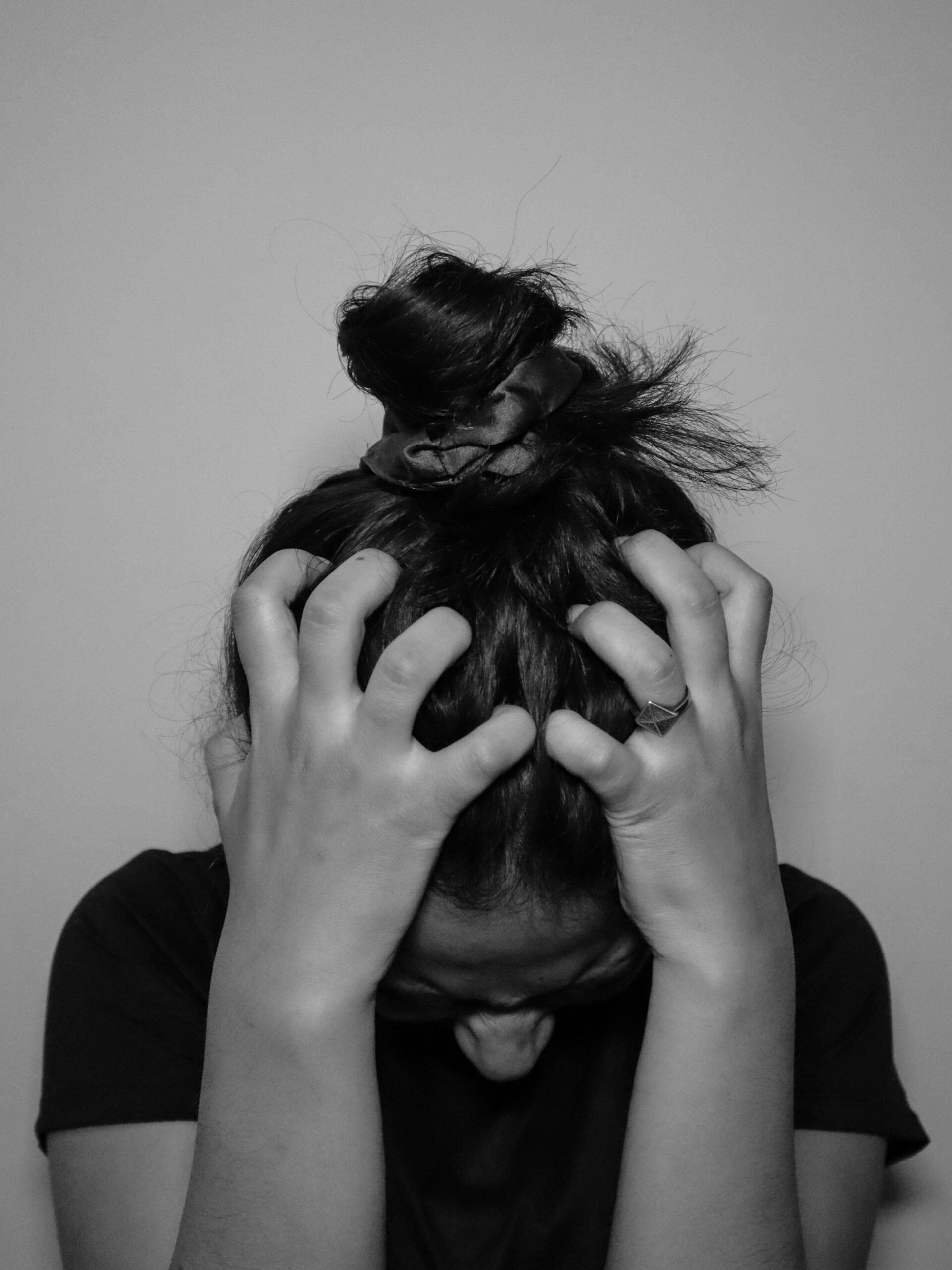 Woman experiencing midlife rage clenches her head in frustration, representing the anger and overwhelm many women feel during perimenopause and midlife transitions